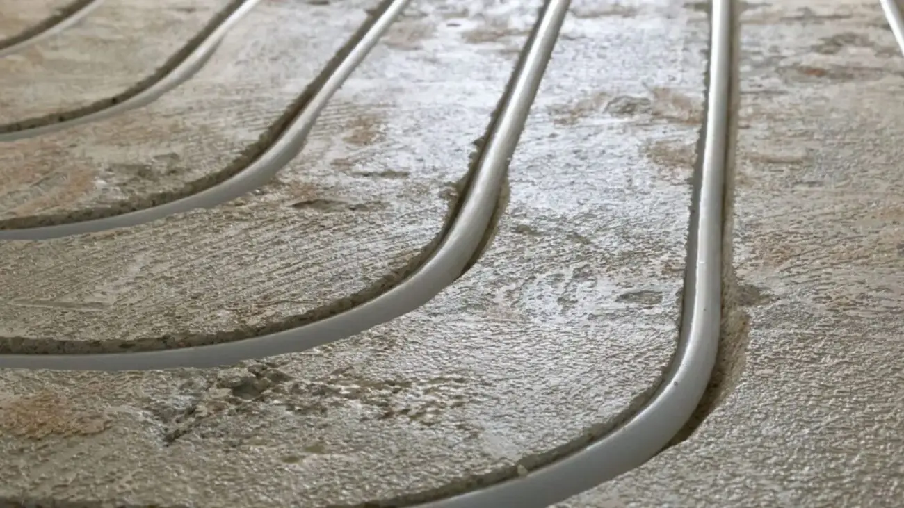 Close-up van strak ingefreesde vloerverwarmingsleidingen in een betonvloer