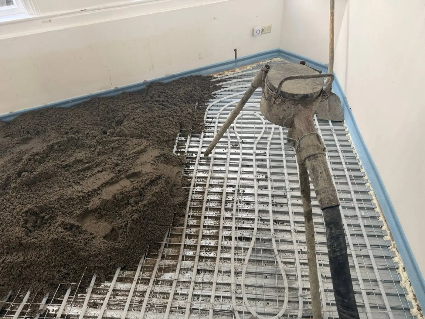 Nieuwe zandcementdekvloer wordt over vloerverwarming op krimpnetten aangebracht